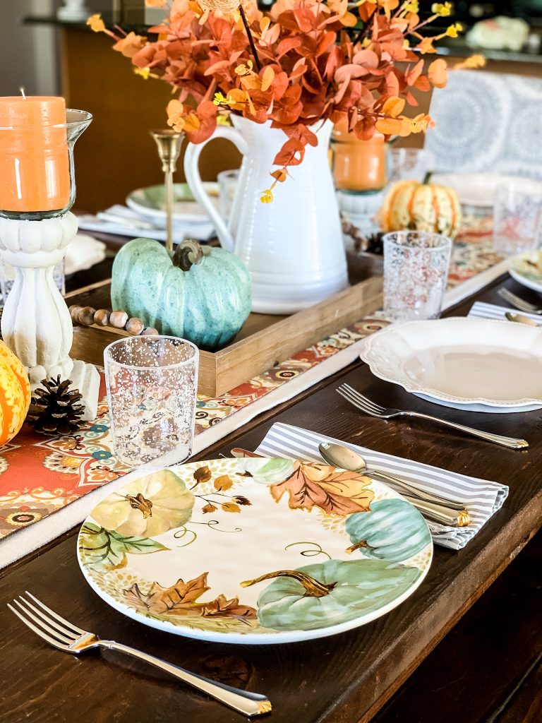 A fall tableseting in colors of teal, orange, greens and rust. 