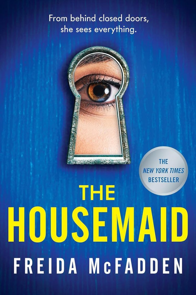 Book cover of the New York Times Bestseller "The Housemaid" by Freida McFadden, featuring a close-up of an eye peering through a keyhole against a textured blue door, shared on Cottage in the Mitten.