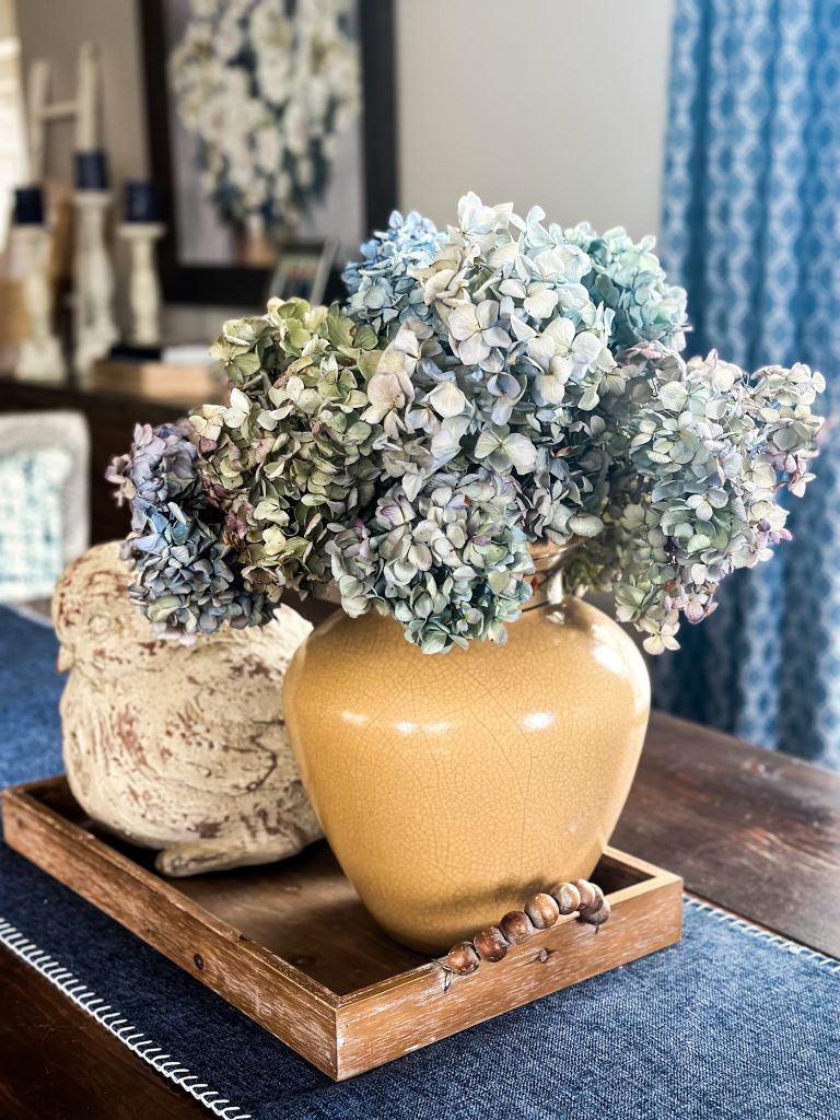 Blue hydrangeas with a stone bird and tray centerpiece for Hygge living.