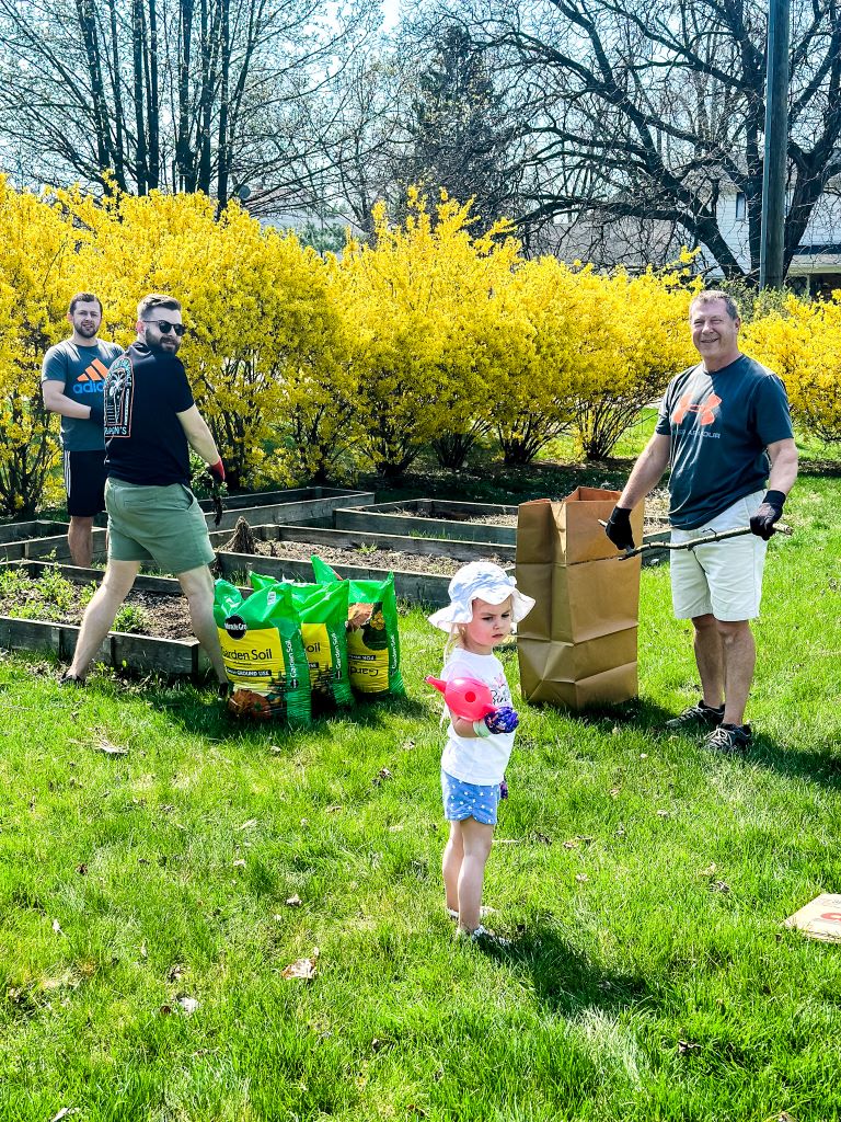 A group of people gathered and filling raised bed with new soil.
