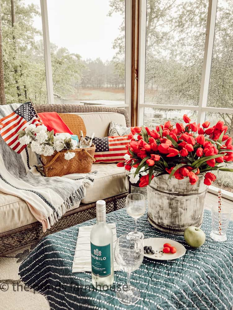 A charming outdoor patriotic picnic setup with red, white, and blue tablecloth, plates, and festive summer decor.