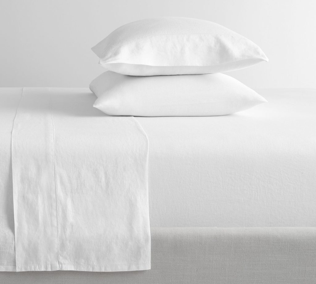 White linen sheets on a bed.