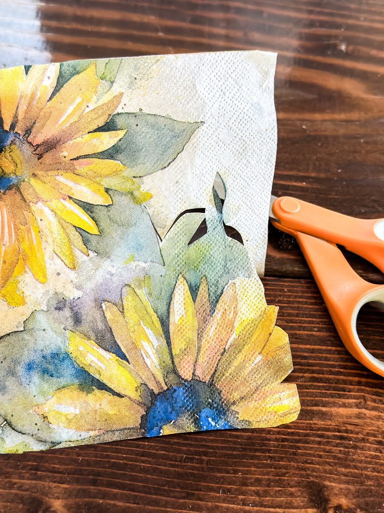 Cutting out a sunflower from a napkin with scissors. 