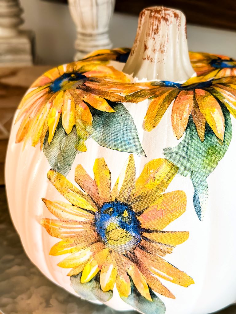 A finished white craft pumpkin that has been decoupaged with sunflower napkins. 