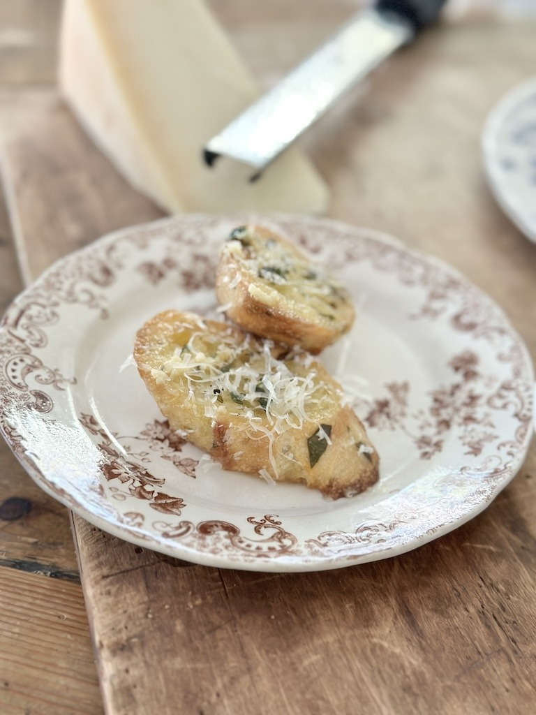 Slices of homemade garlic bread and a brown and white transferware plate.