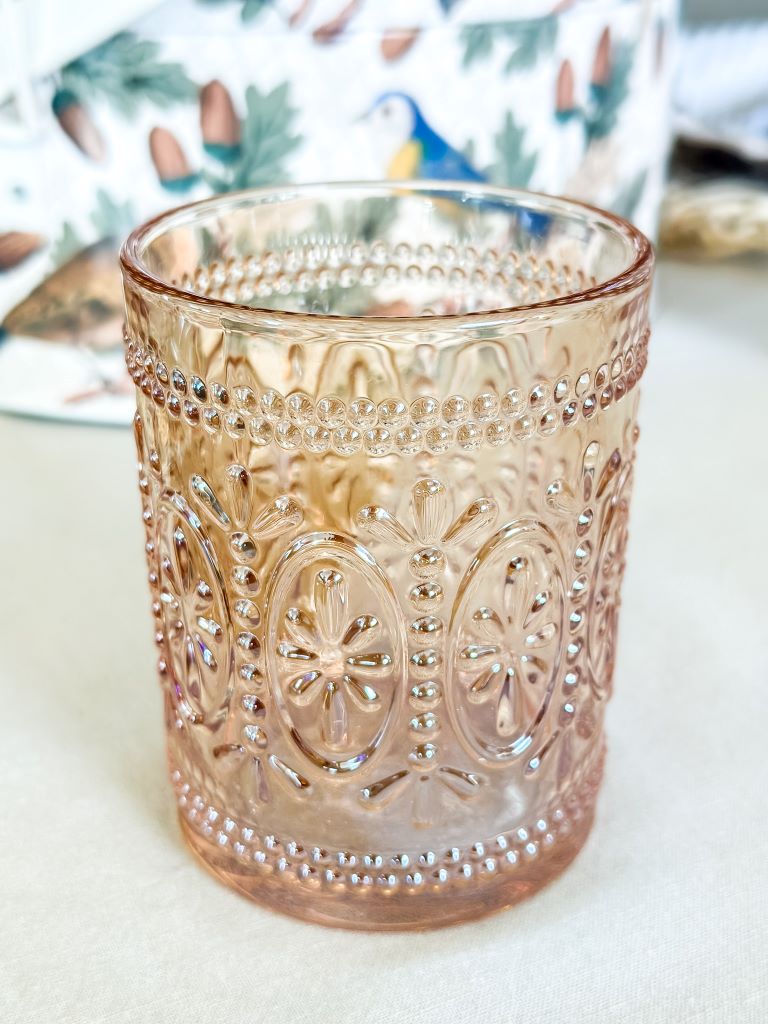 A light amber drinking glass that looks like depression glass sitting on a table. 