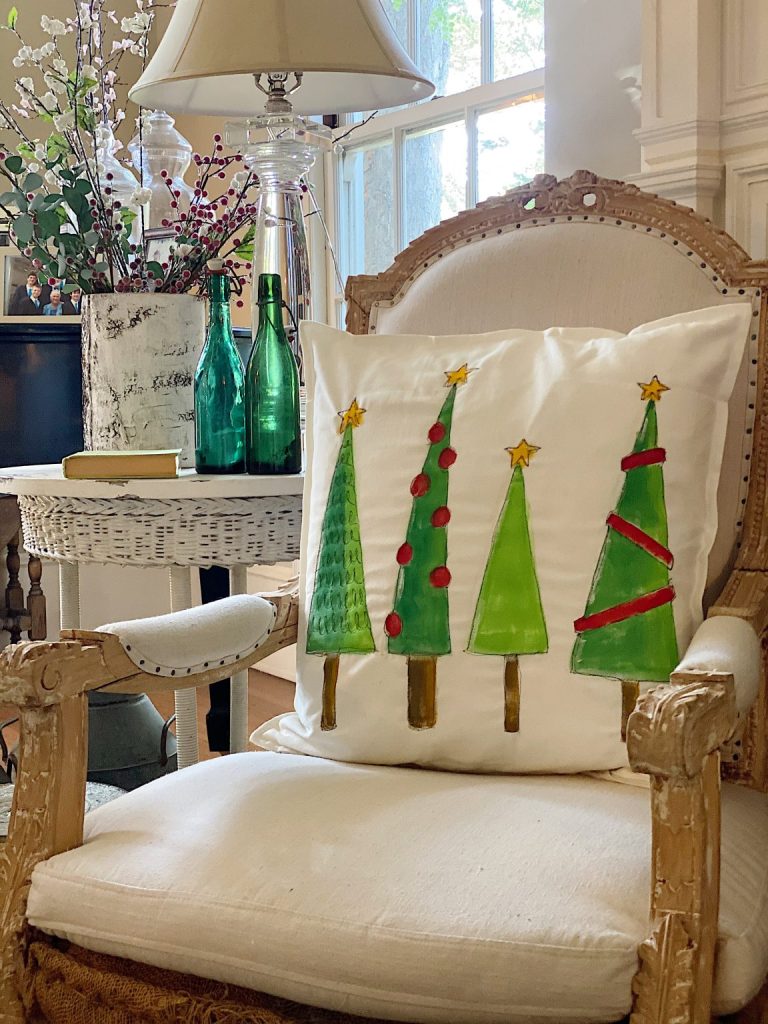 A canvas pillow covered painted with various Christmas tree shapes. 