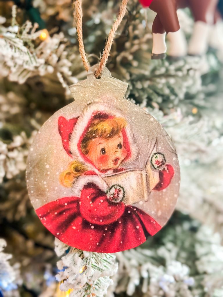 A decoupaged wooden ornament with printed vintage artwork.