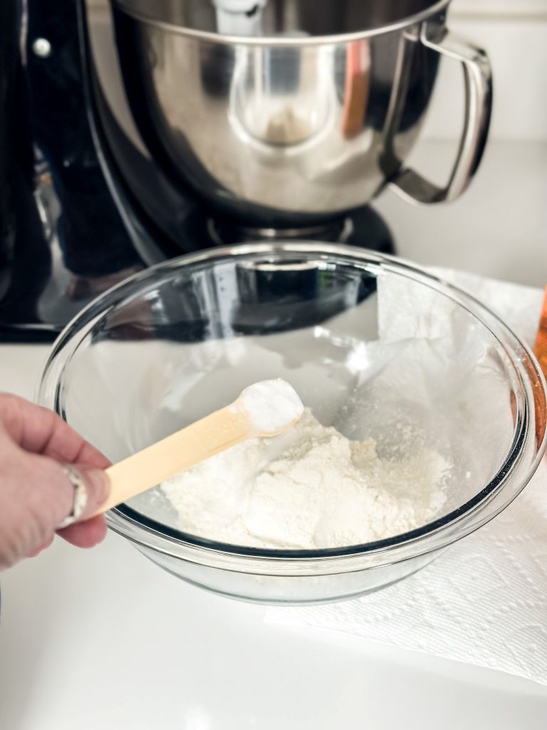 Mixing bowl, glass bowl with dry ingredients and a measuring spoon. 