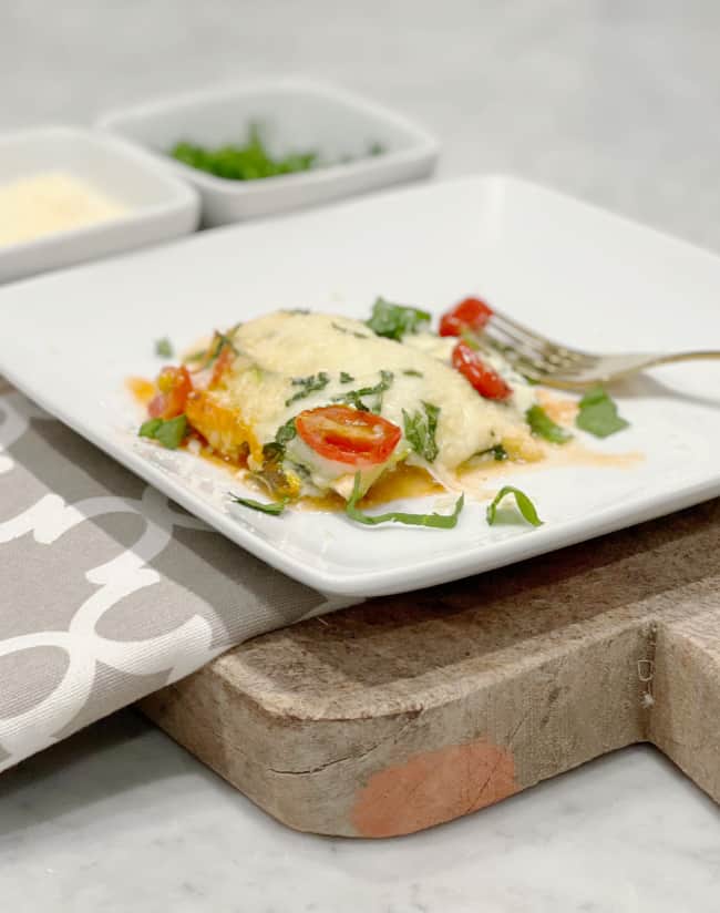 A dish of layered zucchini lasagna with marinara sauce, ricotta cheese, and melted mozzarella on top.