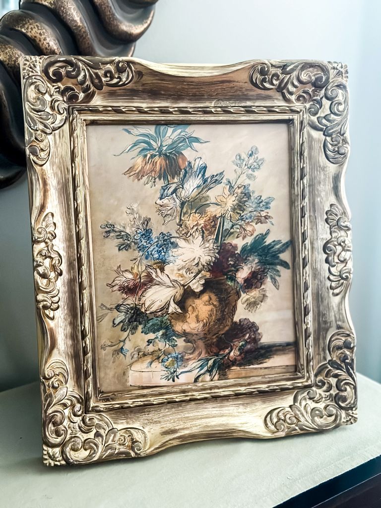 Vintage ornate gold frame featuring a downloaded floral still life art print. A classic cottage-style floral arrangement in a neutral color palette, styled on a console table for a traditional home look.