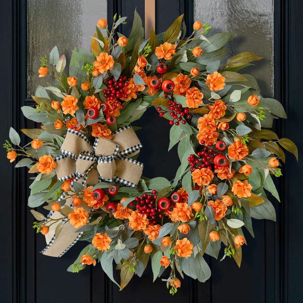 Fall eucalyptus wreath featuring orange wildflowers, red berries, and a burlap buffalo plaid bow.