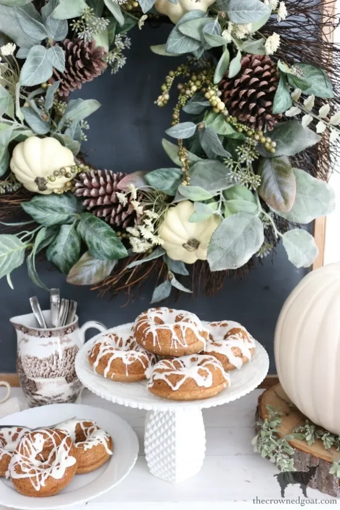 Baked fall spice cake donuts topped with creamy white cream cheese frosting on a serving tray.
