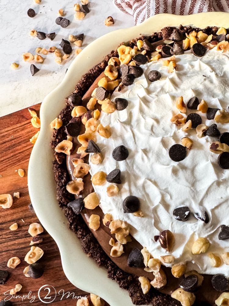 Decadent gluten-free keto chocolate hazelnut pie slice on a plate with a nut crust.